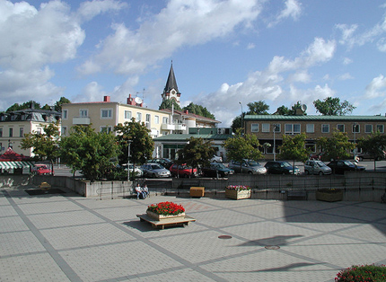 Square, flowers, church tower, parked cars, central buildings